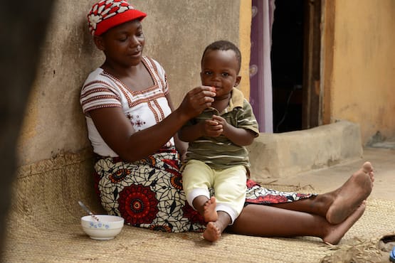 16948708239_f905746d23_o (1) Woman in red cap feeding her son on a woven mat