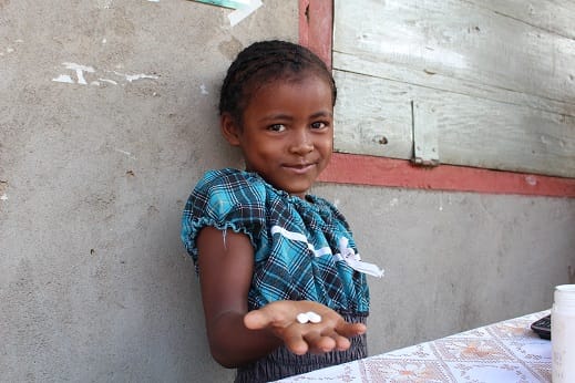 Young girl in Madagascar holding SCI Foundation deworming tablets in her hand