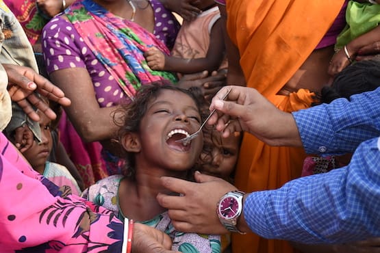 Young girl being fed a deworming pill from Evidence Action