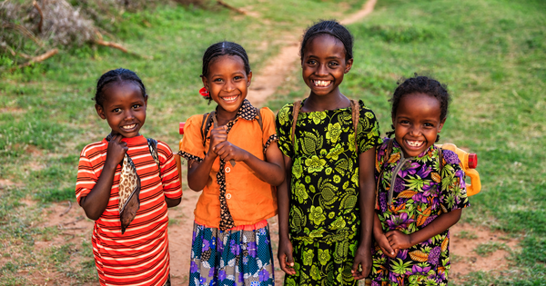 Four young girls in bright clothes standing smiling at the camera.